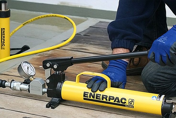 Um homem manuseando umcilindro enerpac amarelo