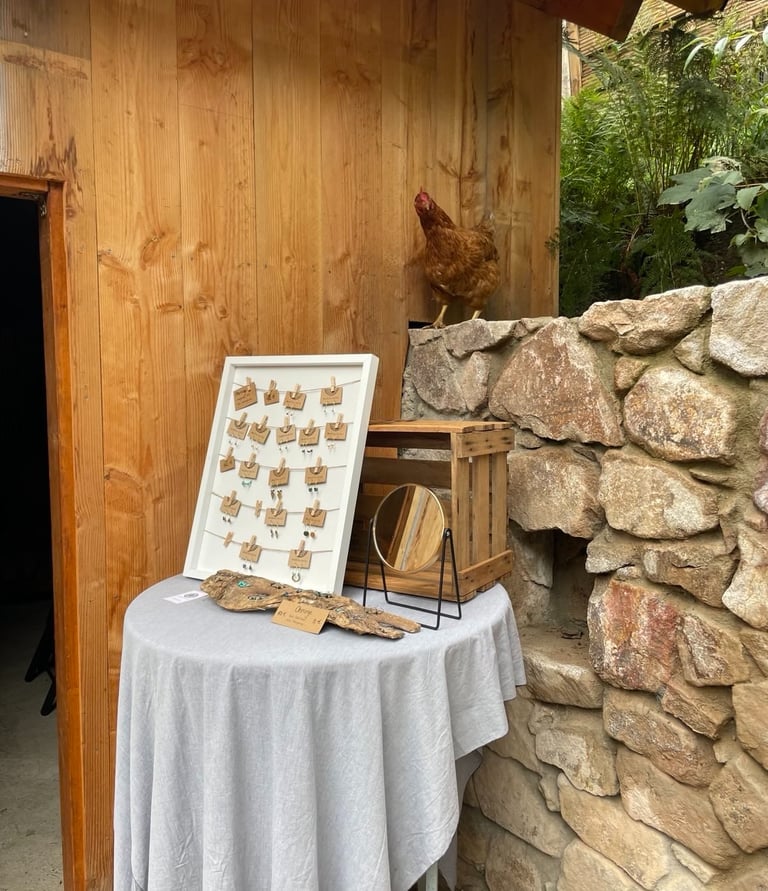 Schmuckausstellung auf Holztisch mit Spiegel und Huhn daneben