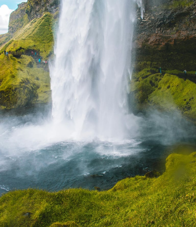 a waterfall in iceland with people standing around it