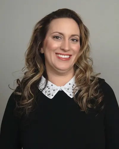 middle aged latin female smiling wearing black blouse white pearl trim