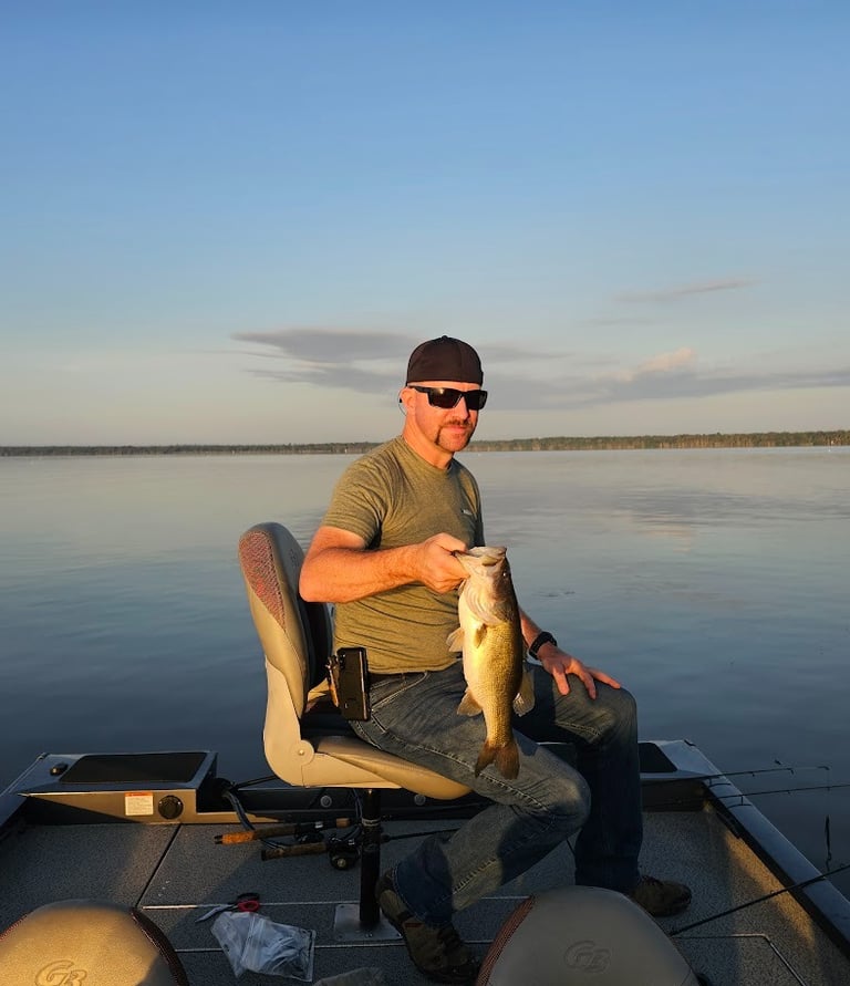 Matt Sitting in boat holding a Large mouth Bass