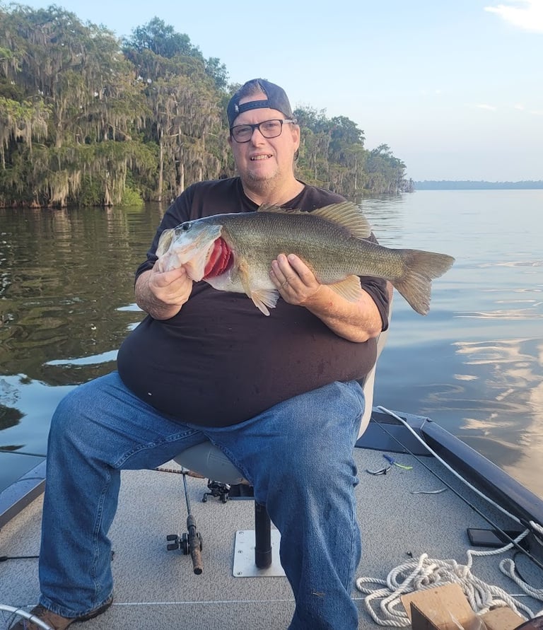 Paul sitting in boat holding a Large Mouth Bass