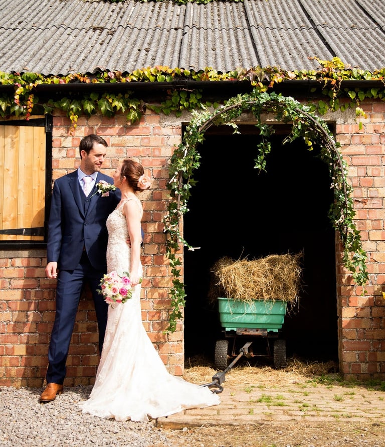 Bride and Groom outside a brick building with an archway, having a informal photoshoot at The Secret Garden wedding venue