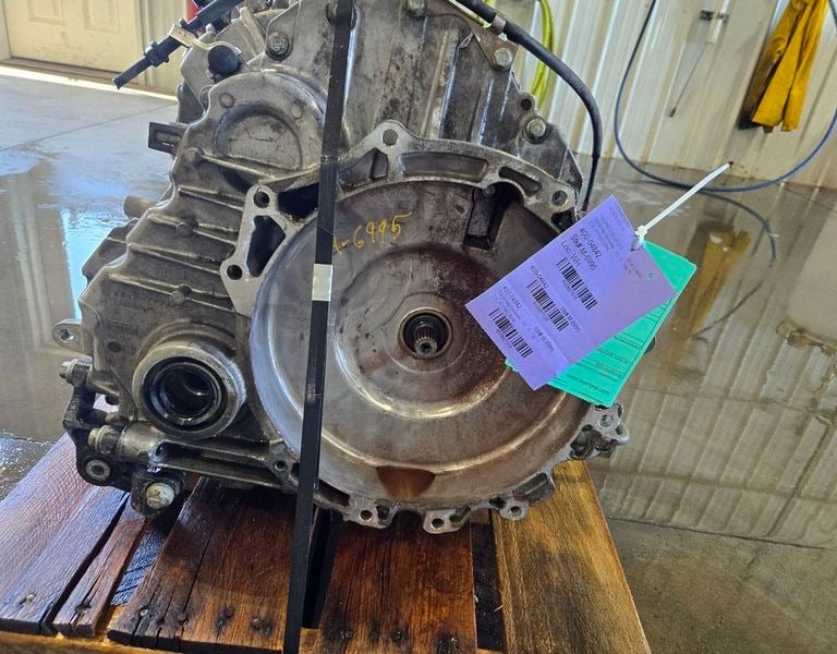 Used car transmission assembly with purple identification tag on a wooden pallet.