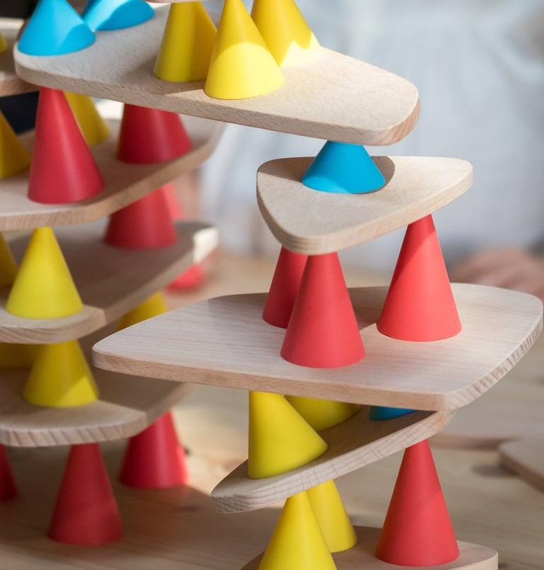 Children creating a structure from colorful silicone cones and wooden tables in the room