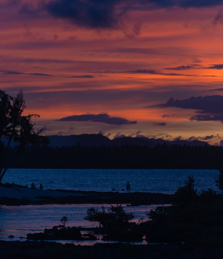 a sunset with a lone bird flying over a body of water