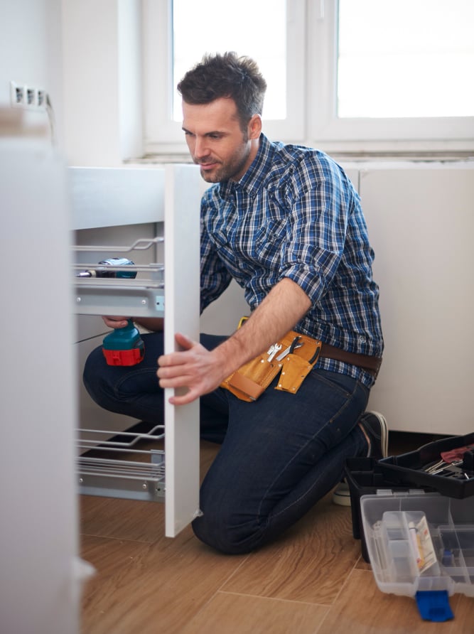 handyman installing kitchen cabinet fittings in an Auckland home