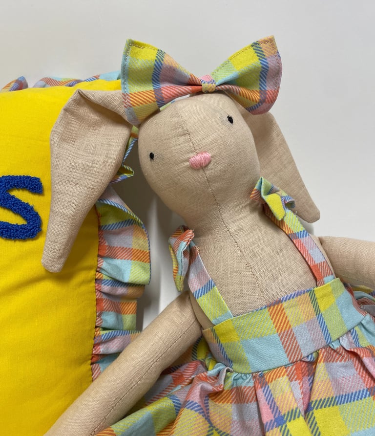 Handmade linen bunny doll wearing a colorful plaid dress and matching bow tie.
