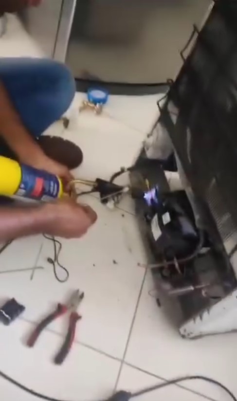 mão do técnico fazendo solda pra conserto de geladeira