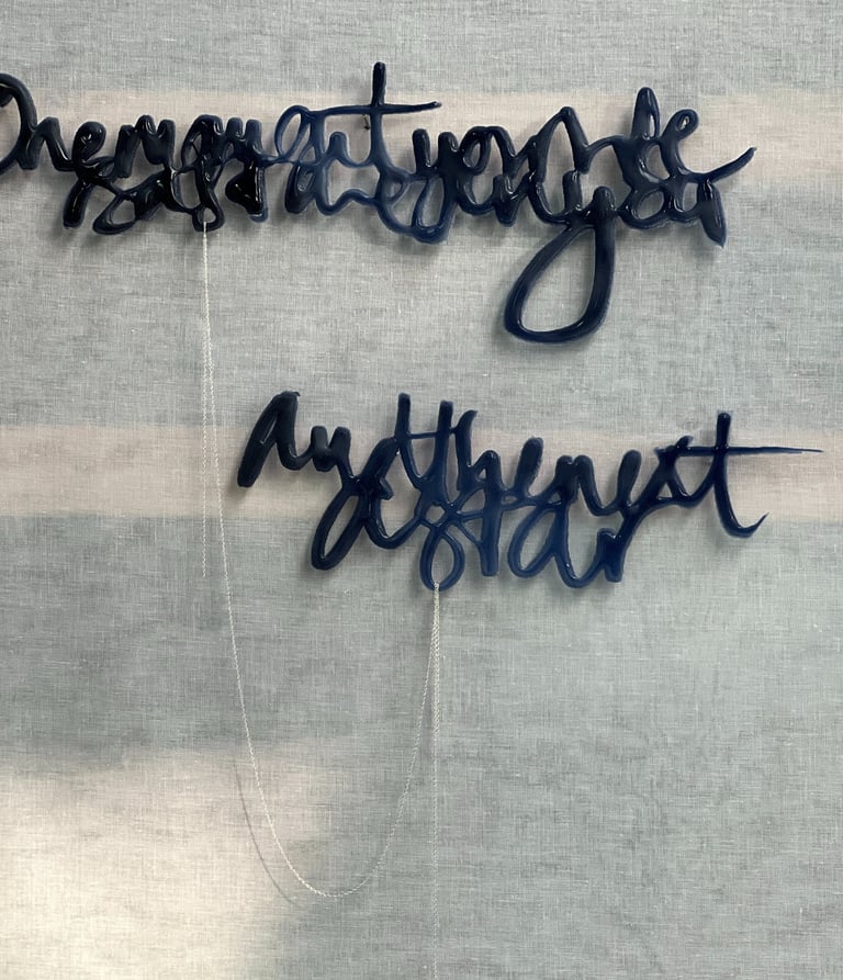 Two lines of semi-abstract text, made in glass and joined by a silver rope chain.