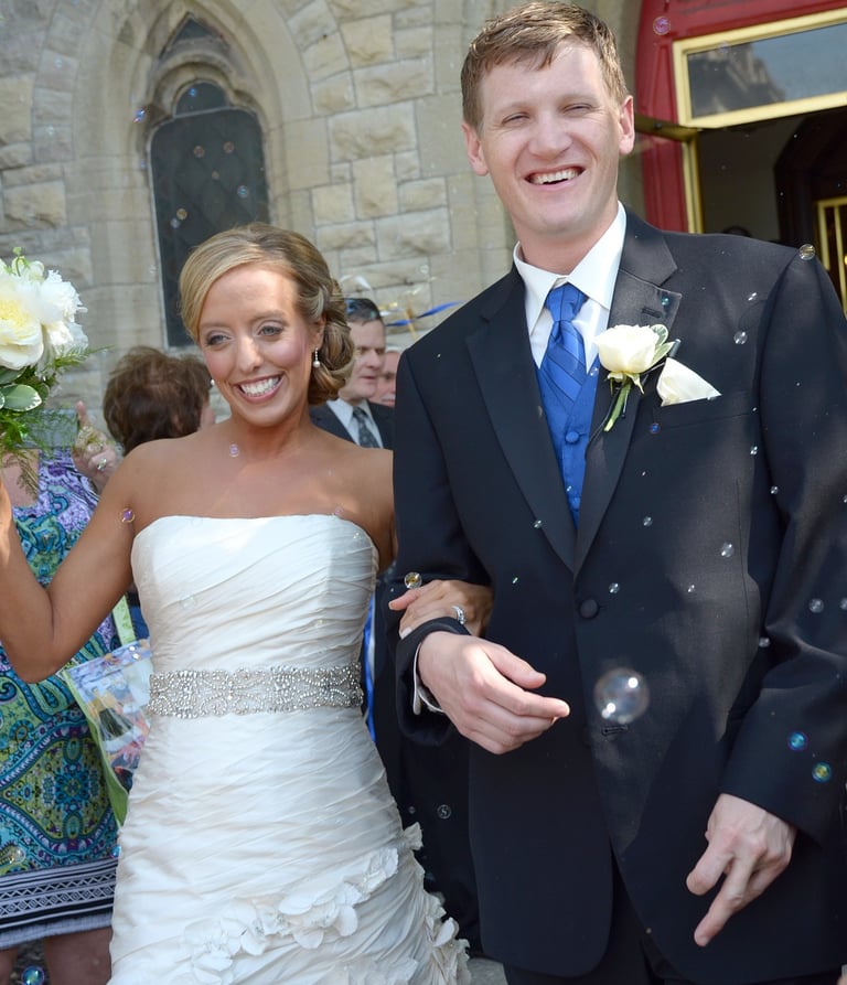 a bride and groom are walking our from the church and bubbles around them