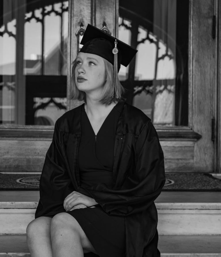 a woman in a graduation gown sitting on a bench