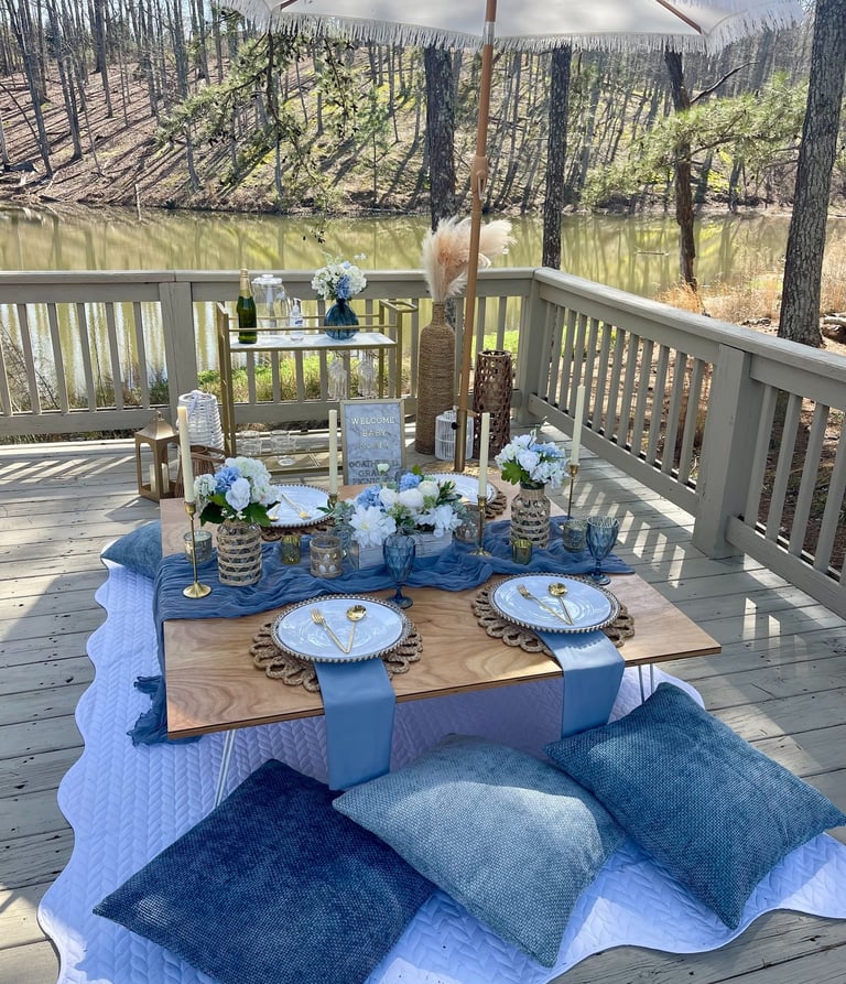 Blue luxury picnic by Gathered Grace Picnic Co with bar cart, umbrella, plush pillow floor seating