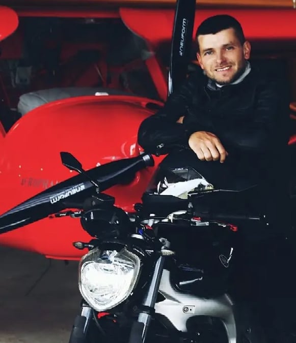 Audrius Turskas a cool man sitting on a motorcycle in a garage next to airplane 