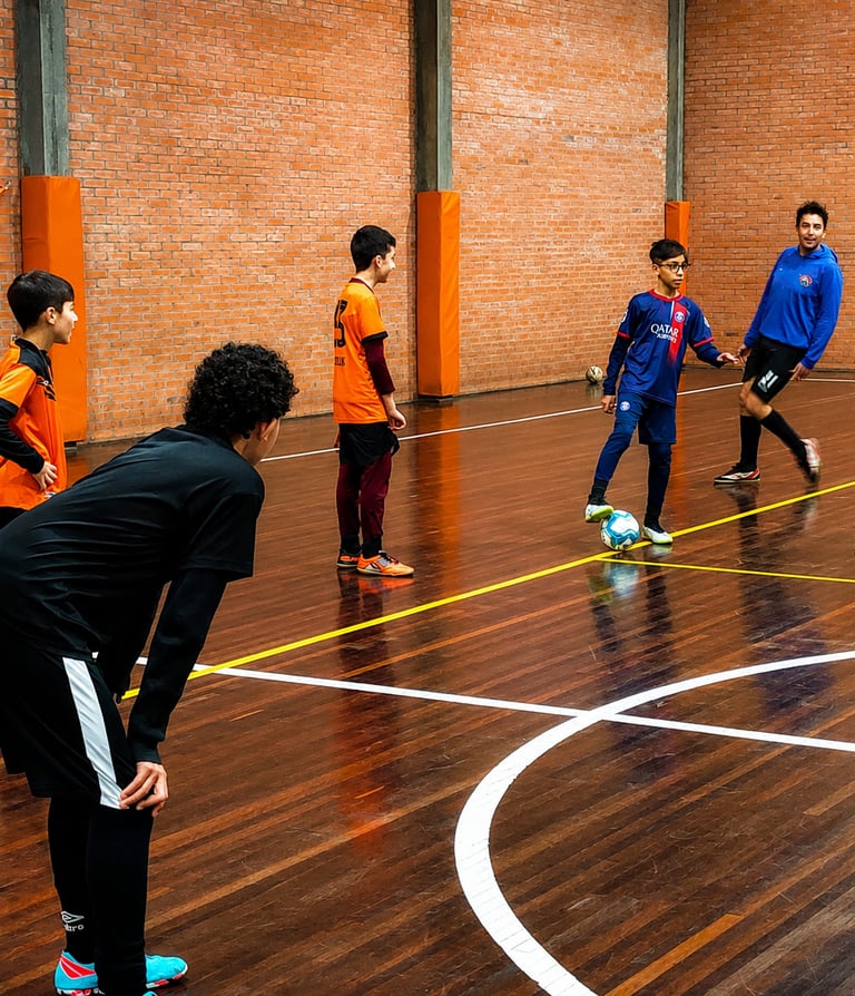 Alunos da escolinha de futsal treinando fundamentos em quadra coberta no Centro Poliesportivo Aviva,