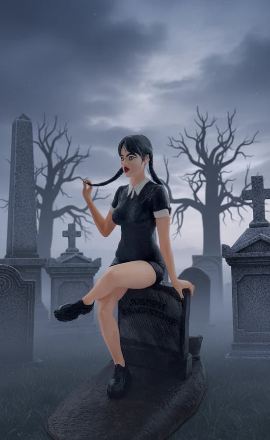 Wednesday Addams figurine sat on tombstone with 'Thing' at the base digging a grave