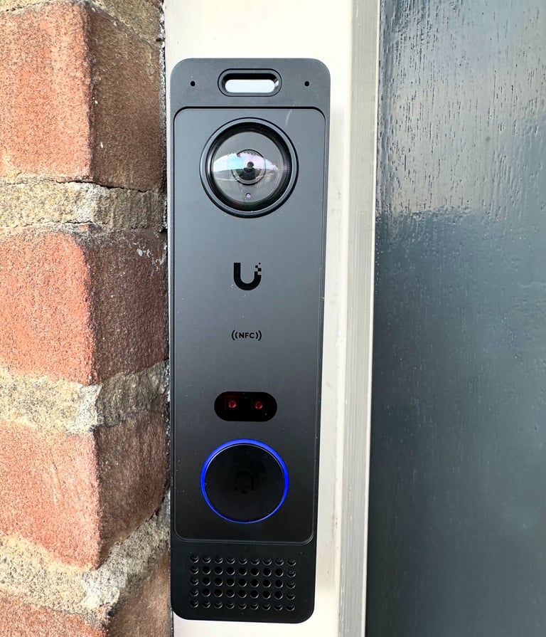 Ubiquiti UniFi G6 Doorbell Pro with camera and NFC reader installed on a brick doorframe.