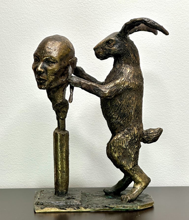 a bronze sculpture of a rabbit carving a human head
