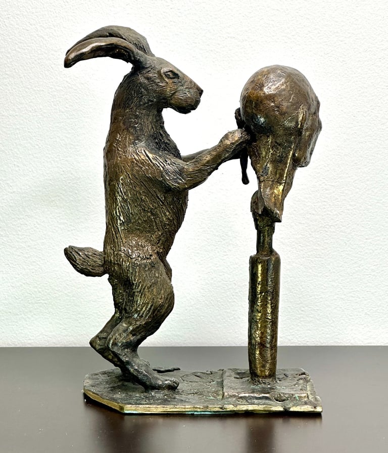 a bronze sculpture of a rabbit carving a human head
