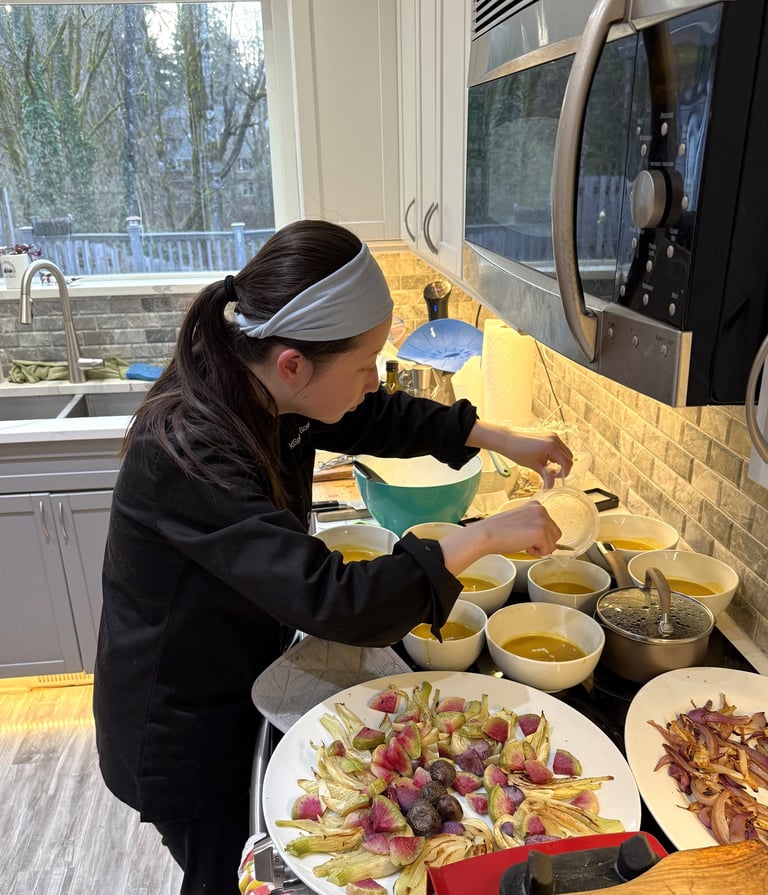 Personal chef Mia plating private fundraiser dinner on-site, soup roasted veg gluten-free dairy-free