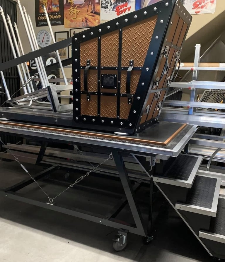 Fire spiker illusion prop featuring a black metal frame and spiked trap door on a rolling table.