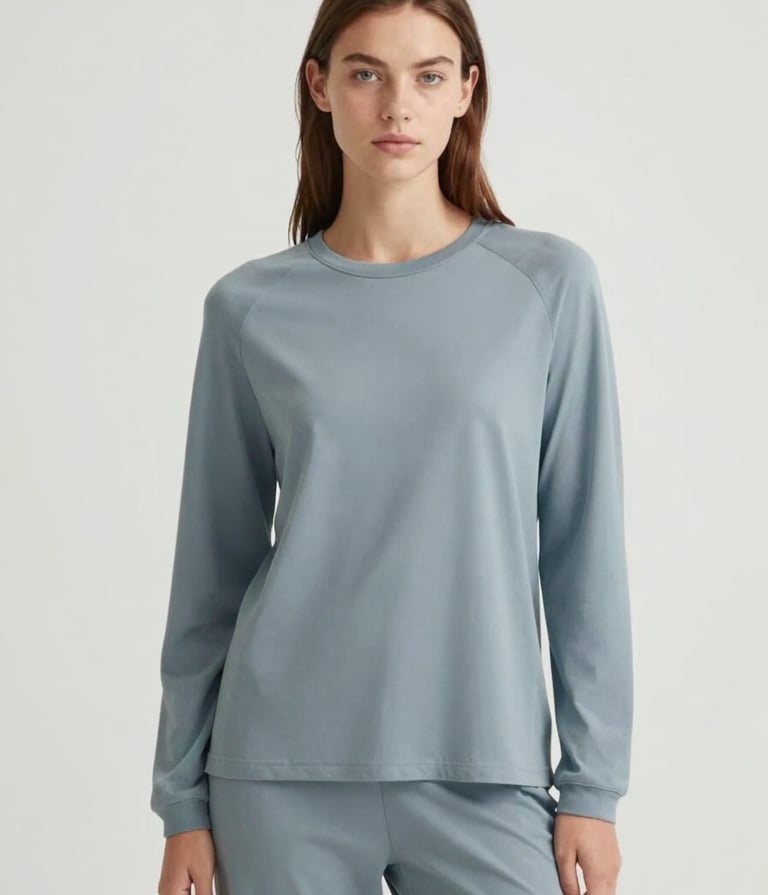 A fashion-forward model with an authentic look posing for a digital campaign. The style is Scandinavian chic, with minimalist clothing in shades of #74A8AE. Professional studio lighting with a clean #ECF3F4 background.