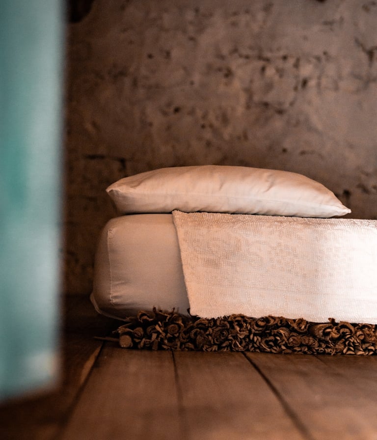 Detail of a bed with white linens in Sardinia, symbol of slow travel and authentic stays