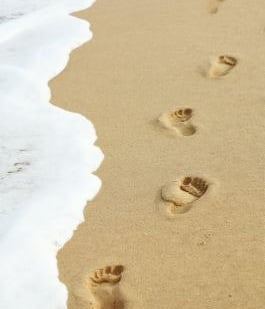 empreintes de pas sur le sable au bord de l’océan symbolisant le chemin en sophrologie humaniste