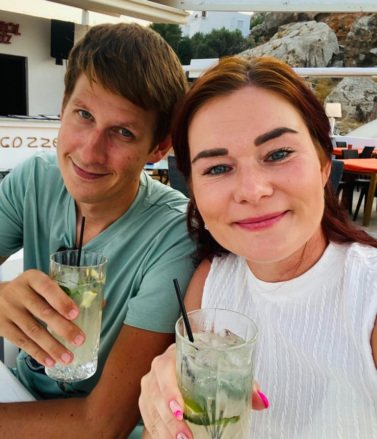 a man and woman sitting at a table with drinks in Rhodes Greece