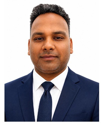 Professional headshot of a smiling Indian man in a dark blue suit and tie, looking directly at the camera.