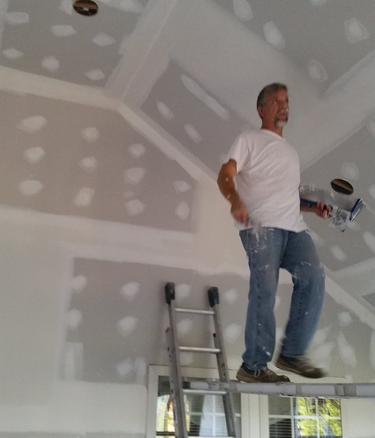Daryl Graybill finishing a ceiling while on a scaffold walk board.