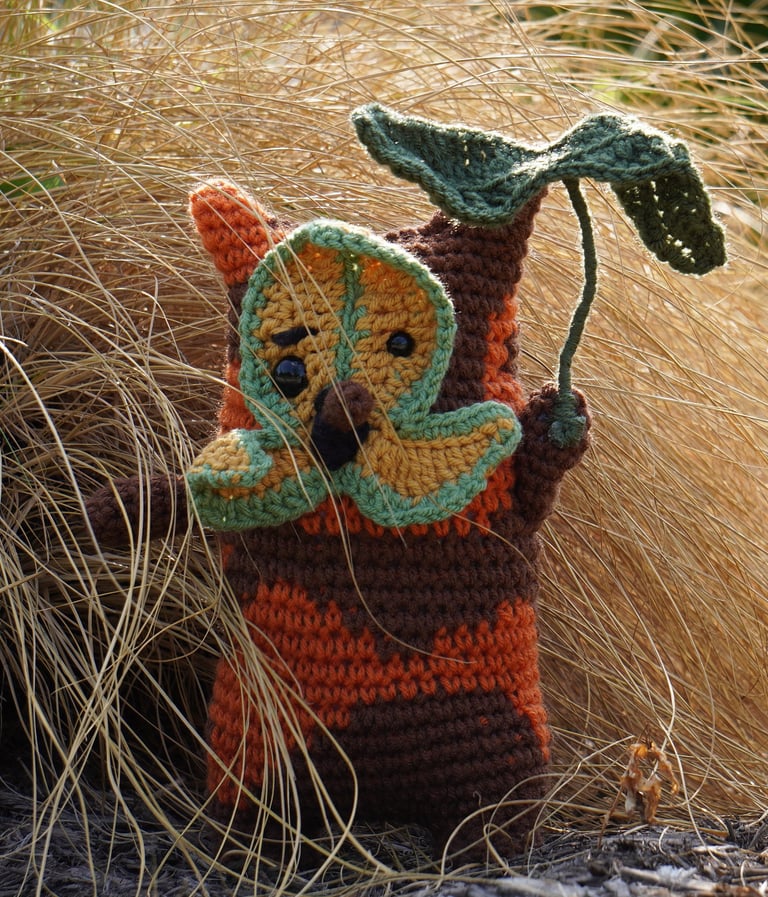 A korok holding a leaf standing in a bush.