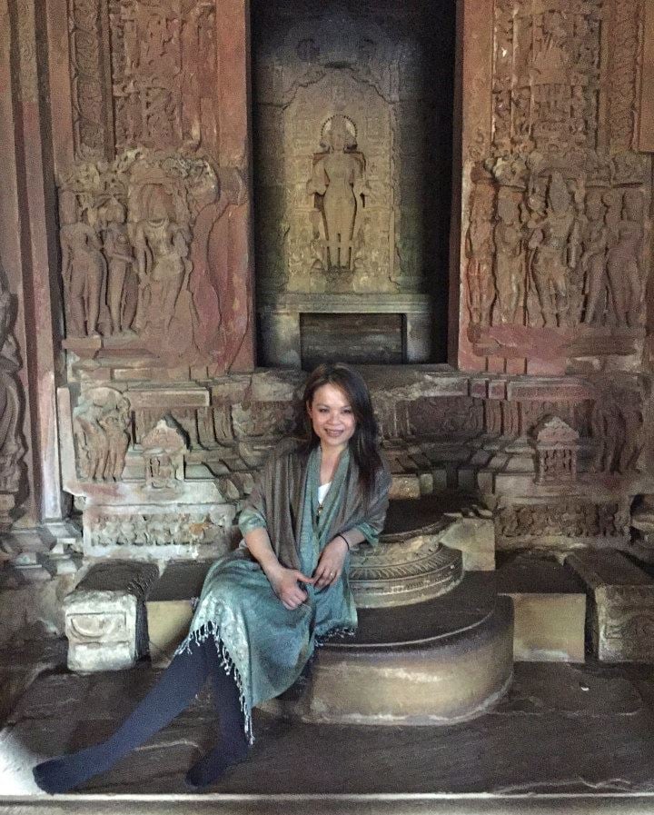 a woman sitting on a stone step with a statue of a woman