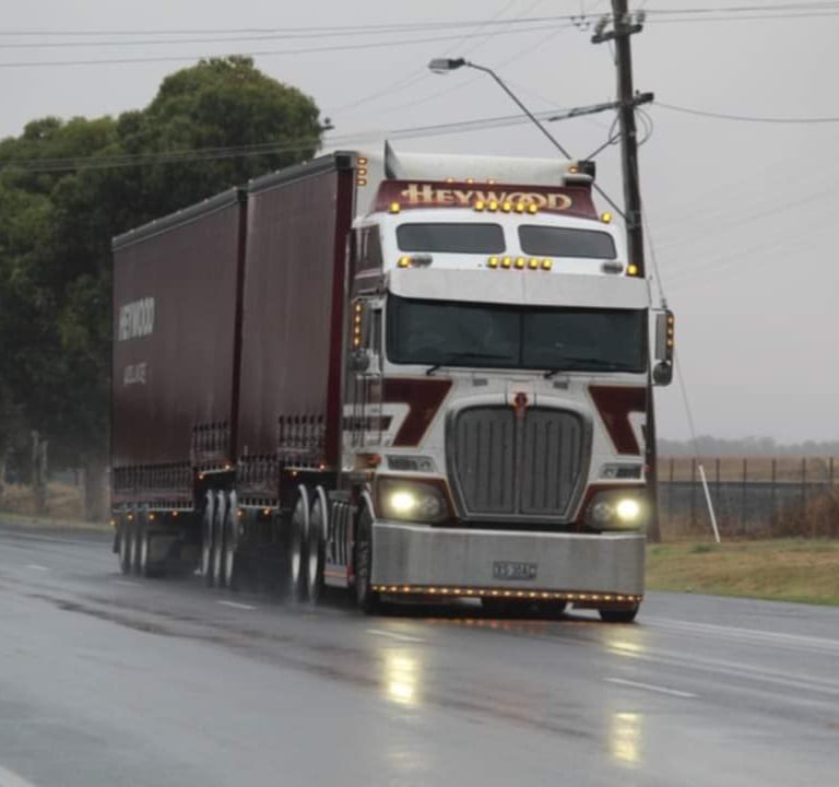 a semi truck driving down a road in the rain