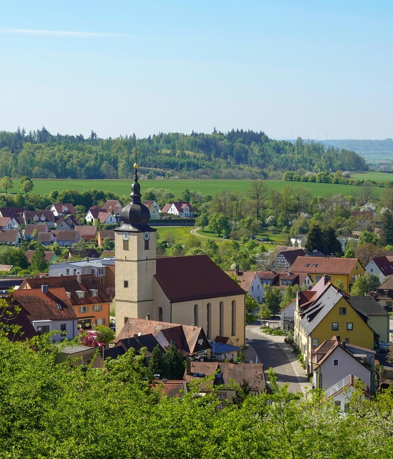 Scenic panoramic view of a traditional German village featuring a historic church tower and red-roofed houses.