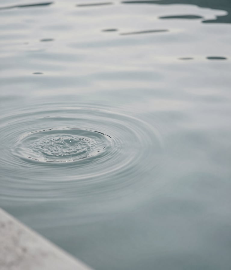 An abstract, minimalist photograph of rippling water in a concrete pool. The tones are muted and neutral, primarily #D0D5DB and #2F363F, reflecting the sky.