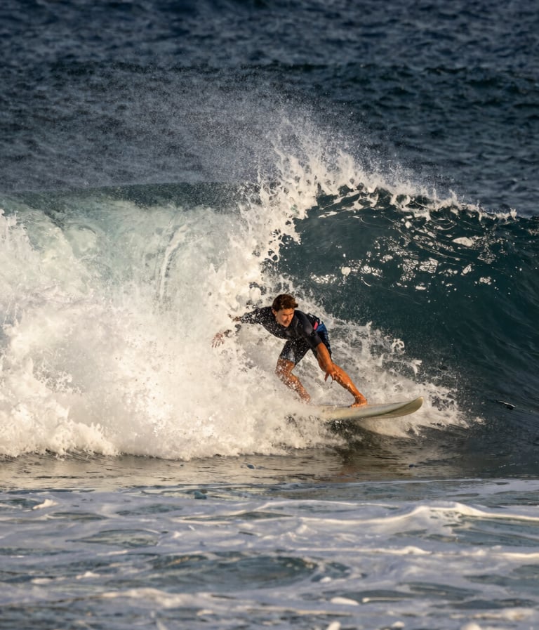 A professional surfer navigating a powerful barrel wave, Western / International coastal setting, high contrast lighting, spray of water caught in mid-air, dark midnight blue ocean and off-white sea foam.