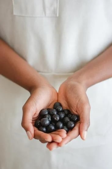 une femme tenant une poignée de myrtilles dans ses mains.