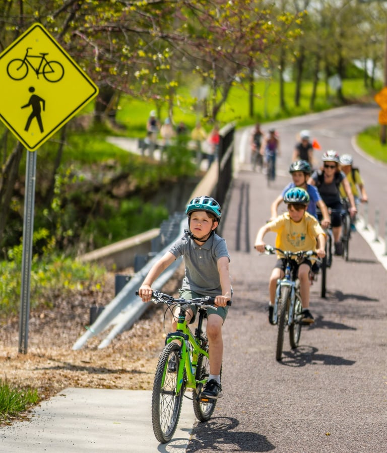 Photo of a bunch of kids riding on a sidewalk over a bridge
