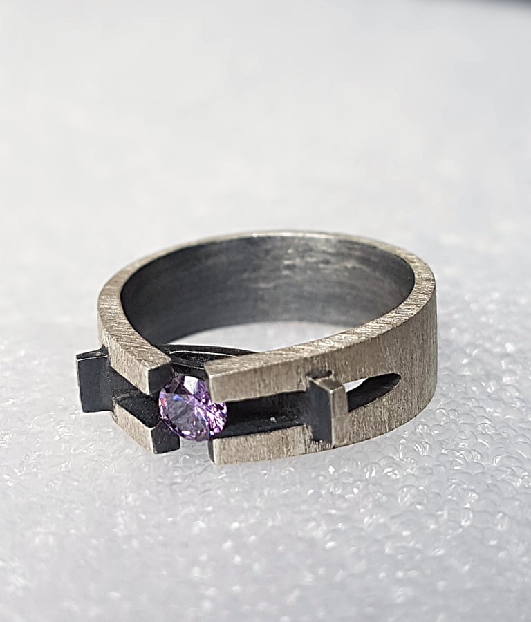 a ring with a purple stone ring on top of a white surface