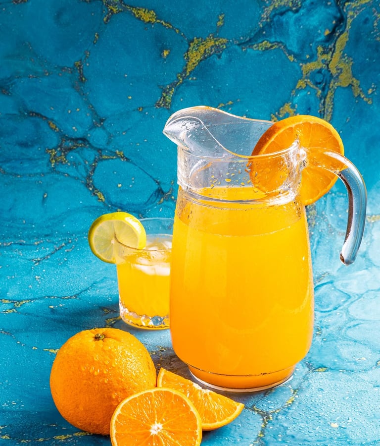 a pitcher of orange juice with oranges and lemon