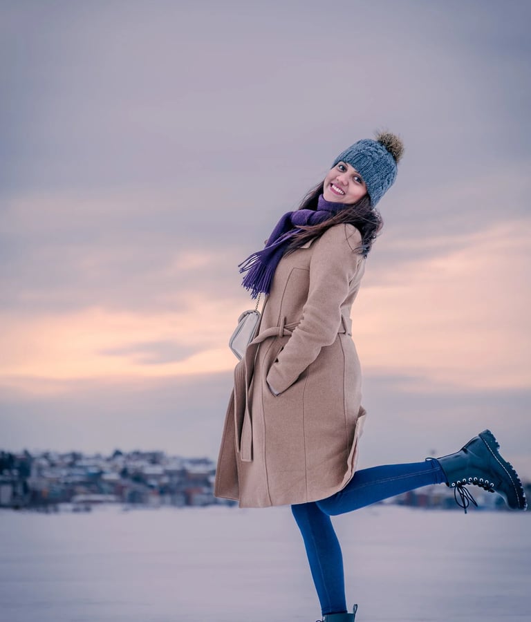 a woman in a coat and hat standing in the snow