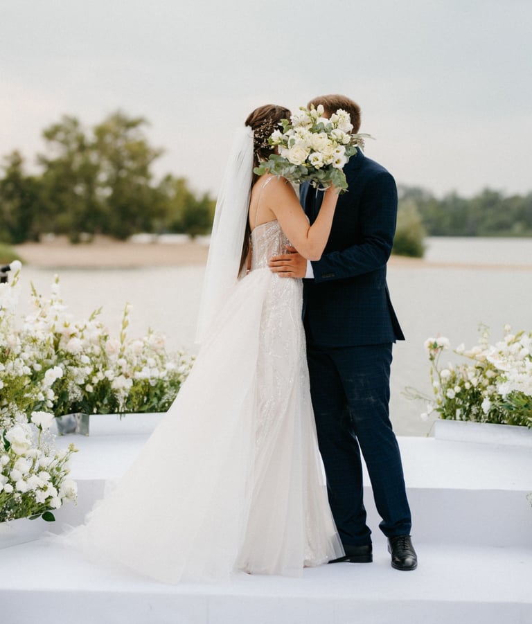 Bride and groom kiss at outdoor ceremony, bouquet raised—filmed by Imack Wedding Films, Glasgow.