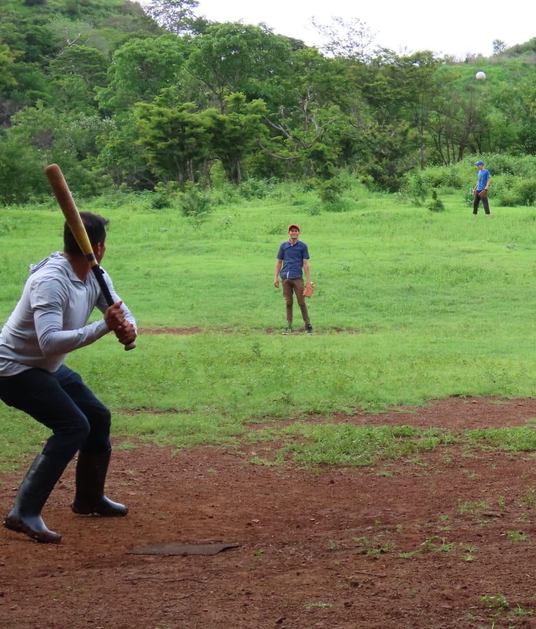A group of young men playing baseball in a rural countryside.