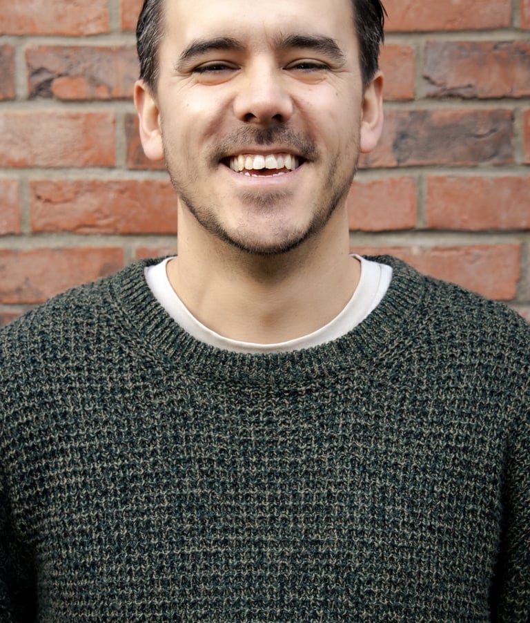 a man smiling in front of a brick wall background