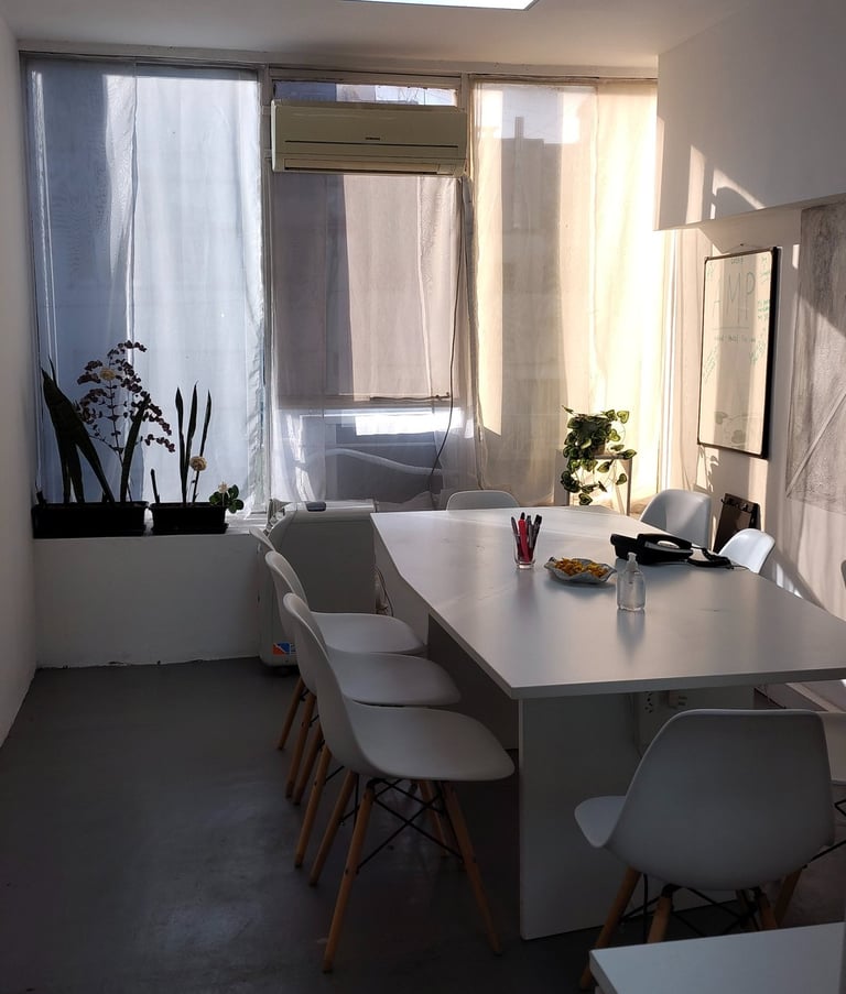 Sala de firmas en Red de Llaves con mesa blanca, sillas modernas y luz natural entrando por el ventanal.
