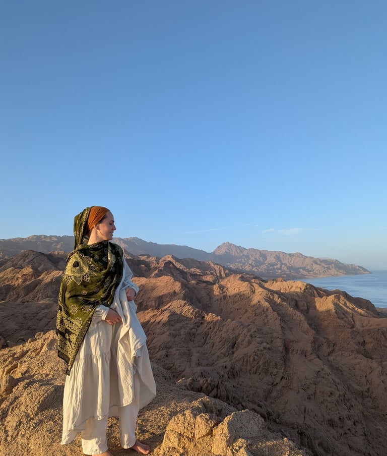 Woman standing on top a mountain with ocean in the background