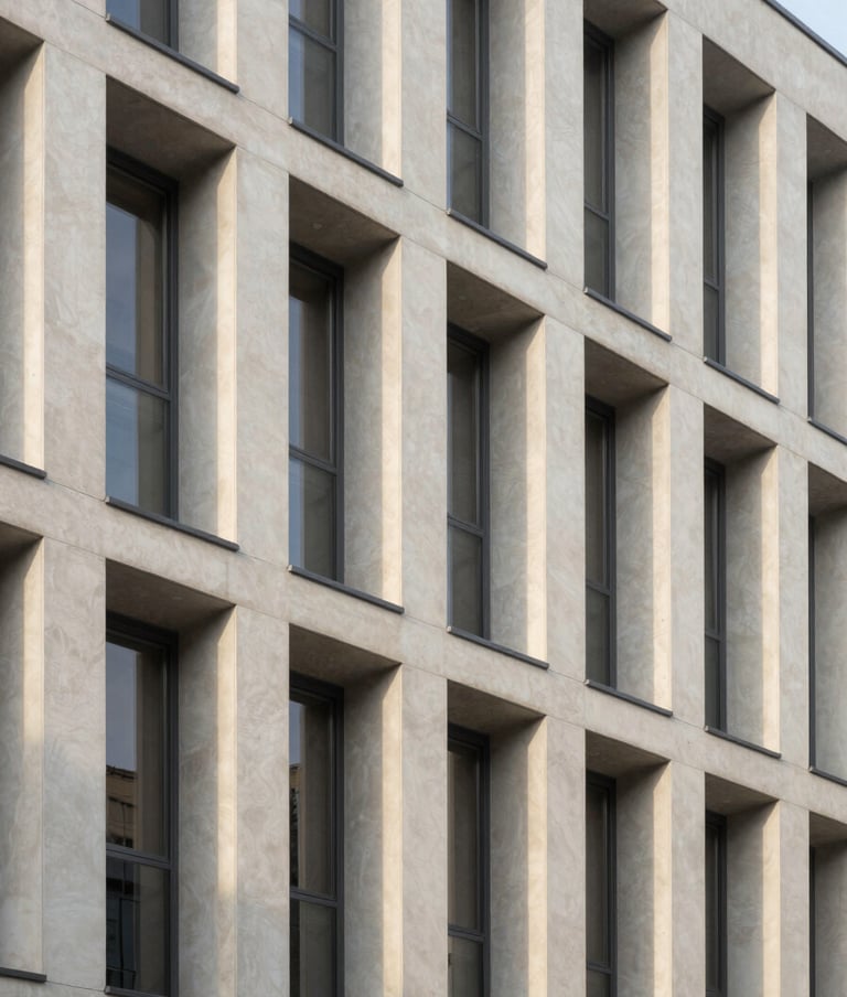 Architectural photography of a modern minimalist building facade in a Central European city, clean lines, soft afternoon sunlight casting long shadows, soft off-white and light silver grey palette.