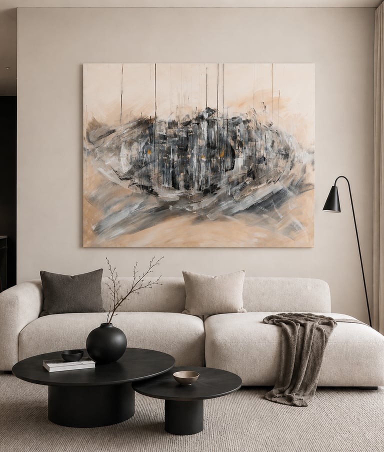 Minimalist living room featuring a curved beige sofa, large abstract wall art, and black nesting coffee tables.