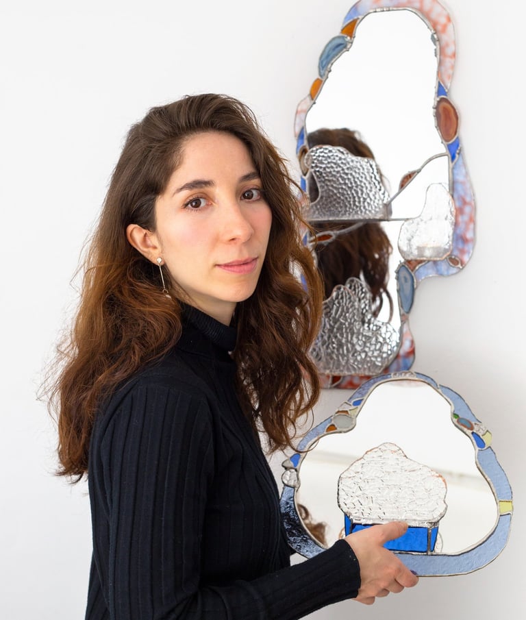 Artista sosteniendo un espejo artesanal de vitral con forma orgánica y un borde de mosaico